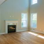 Salon fraîchement peint en vert sauge à Montréal avec de hauts plafonds et un manteau de cheminée blanc, montrant pourquoi vous devriez peindre l'intérieur de votre maison.