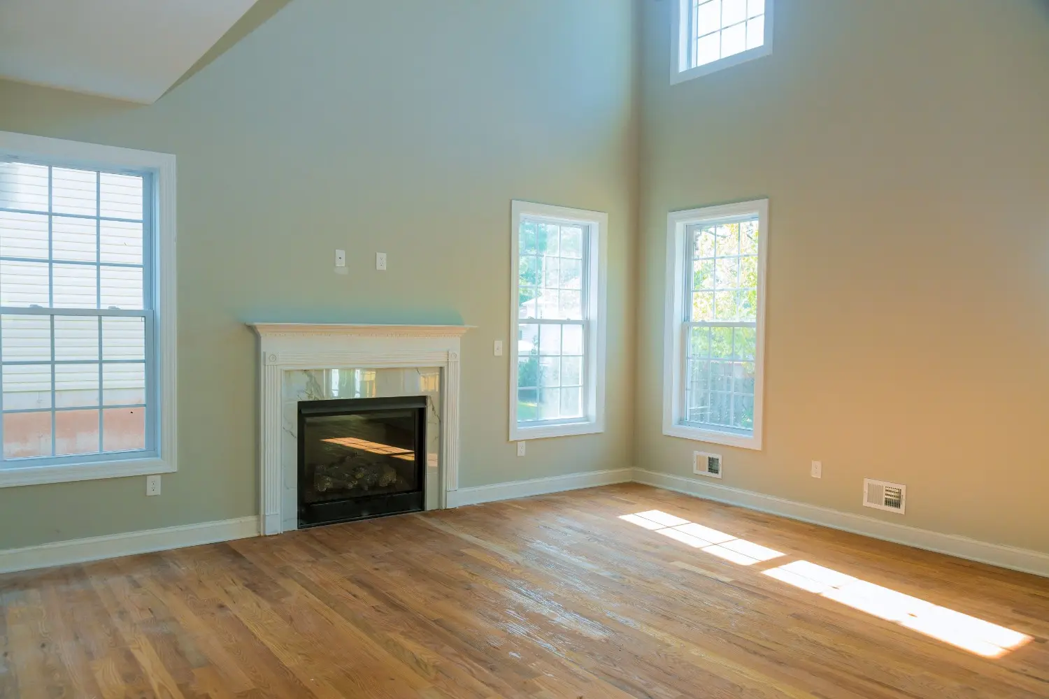 Salon fraîchement peint en vert sauge à Montréal avec de hauts plafonds et un manteau de cheminée blanc, montrant pourquoi vous devriez peindre l'intérieur de votre maison.