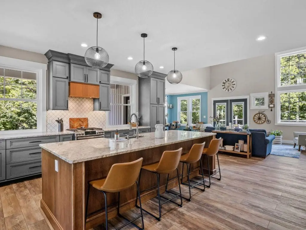 Modern open-concept kitchen featuring gray shaker cabinets, a wood island with leather stools, and professional interior finishes by Pro Paint Plus.